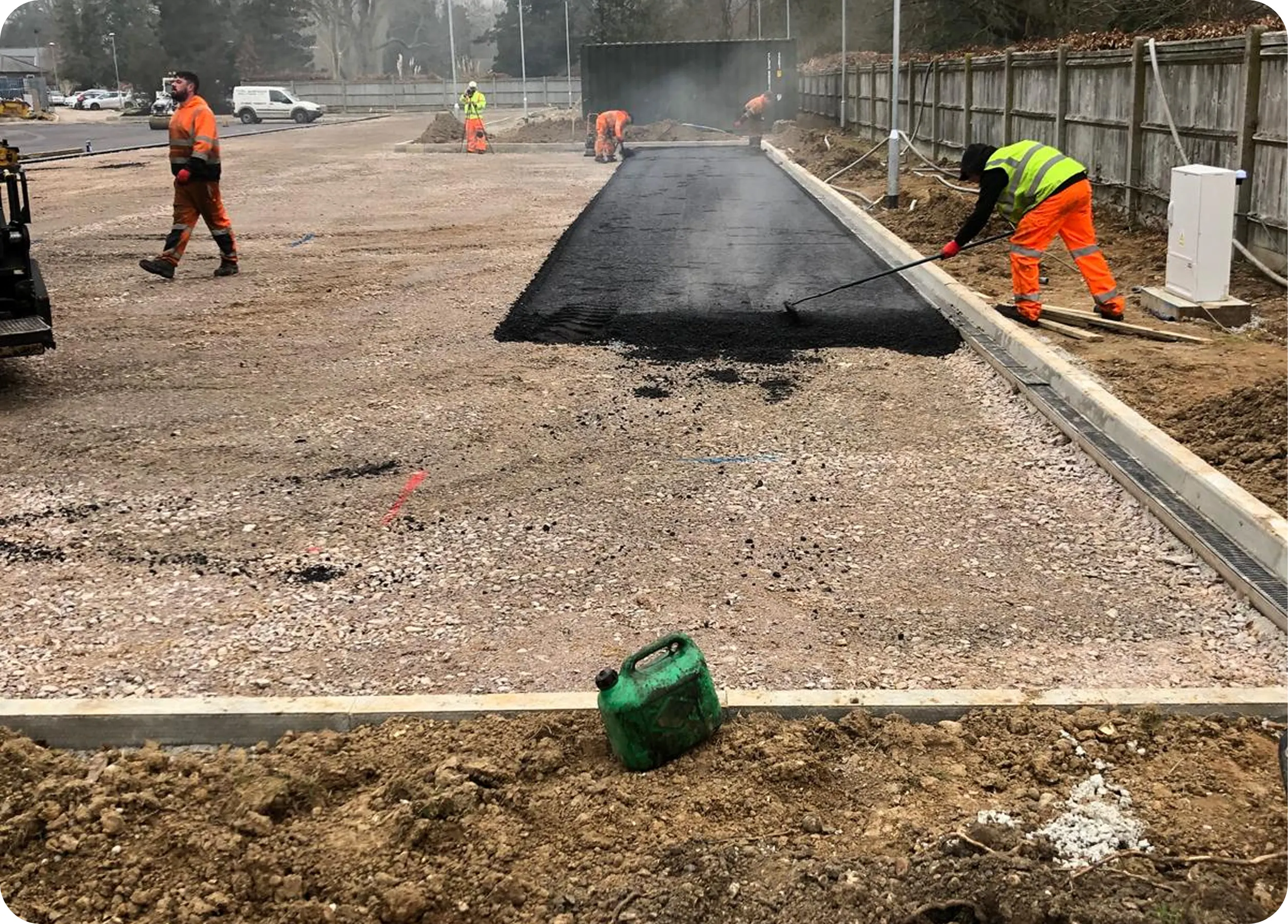 Crew laying tarmac along a new kerb line