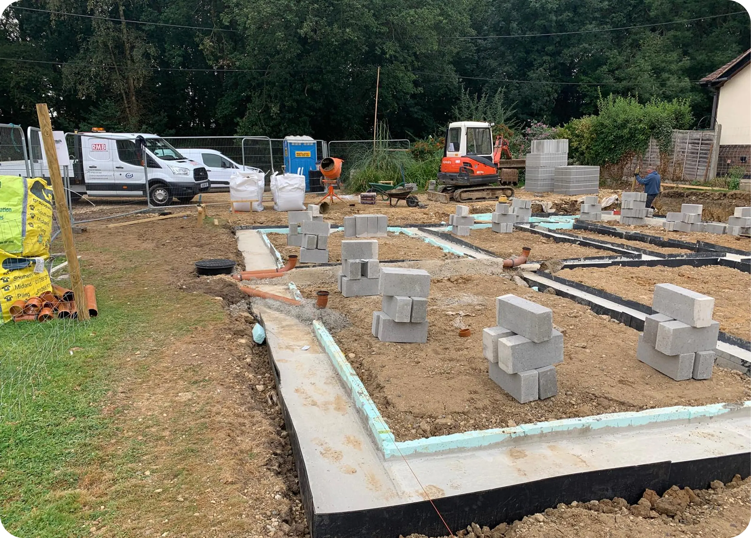 Drainage and blockwork on a house foundation with an RMB van