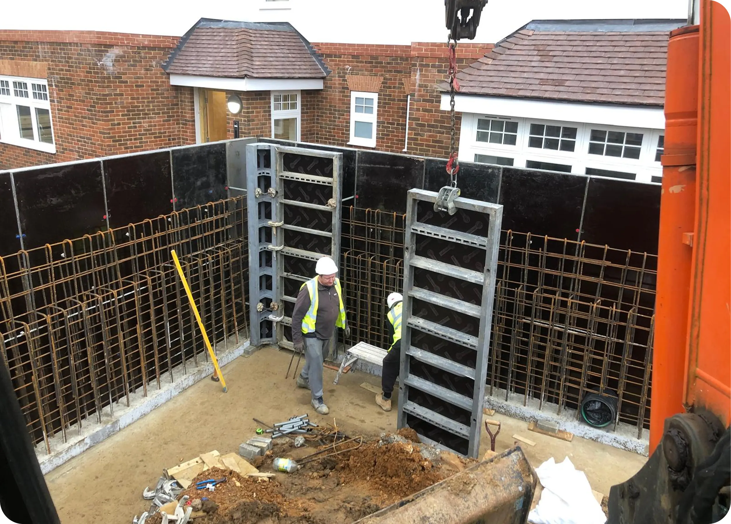 Steel formwork being lifted into a basement excavation