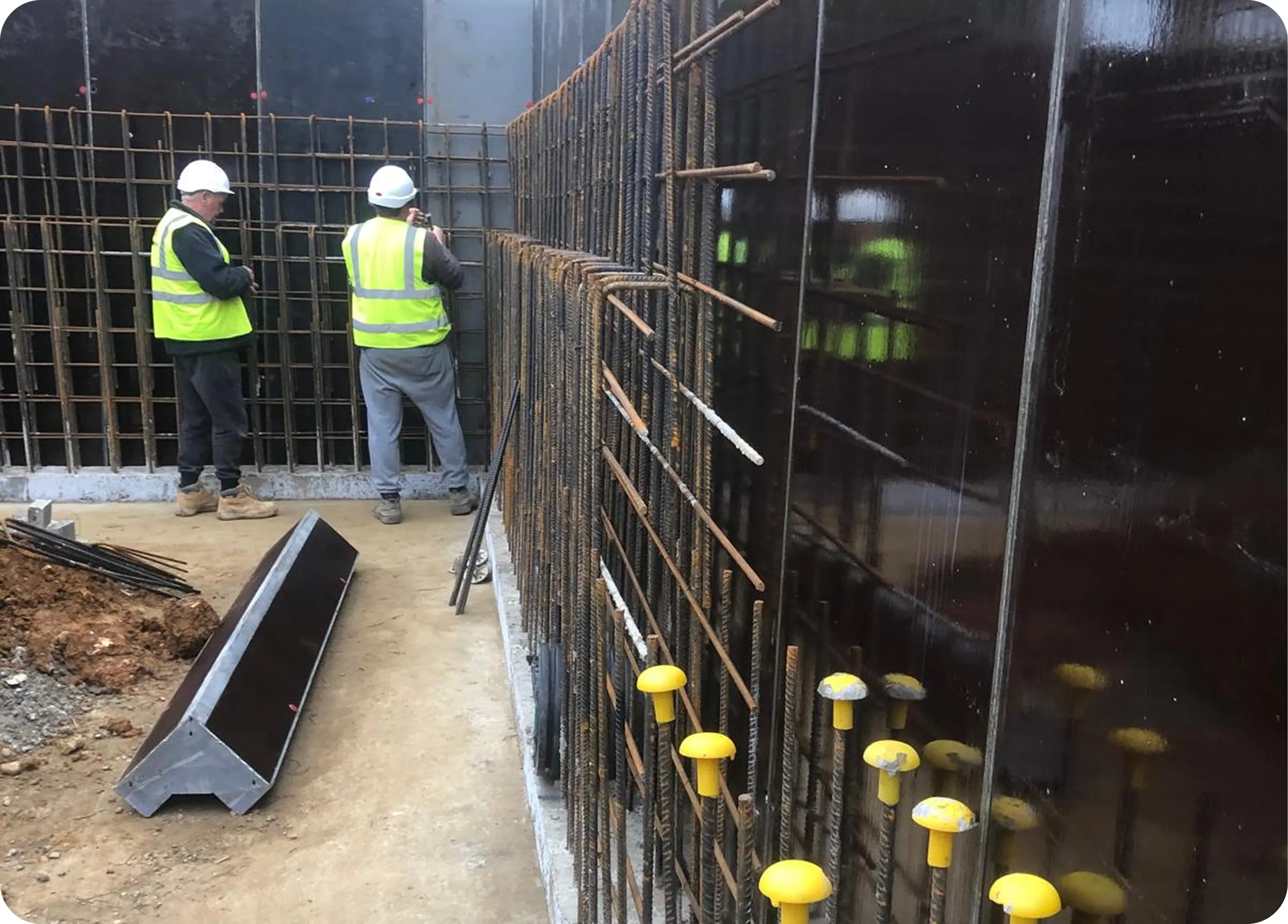 Operatives fixing reinforcement against basement formwork