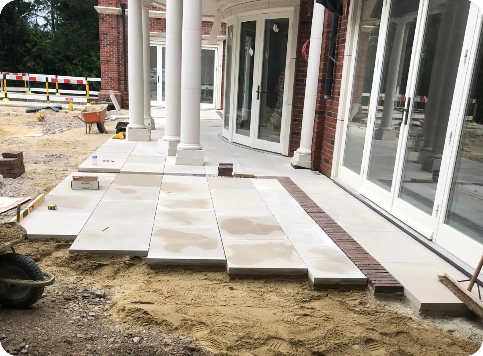 Stone paving being laid around a residential colonnade